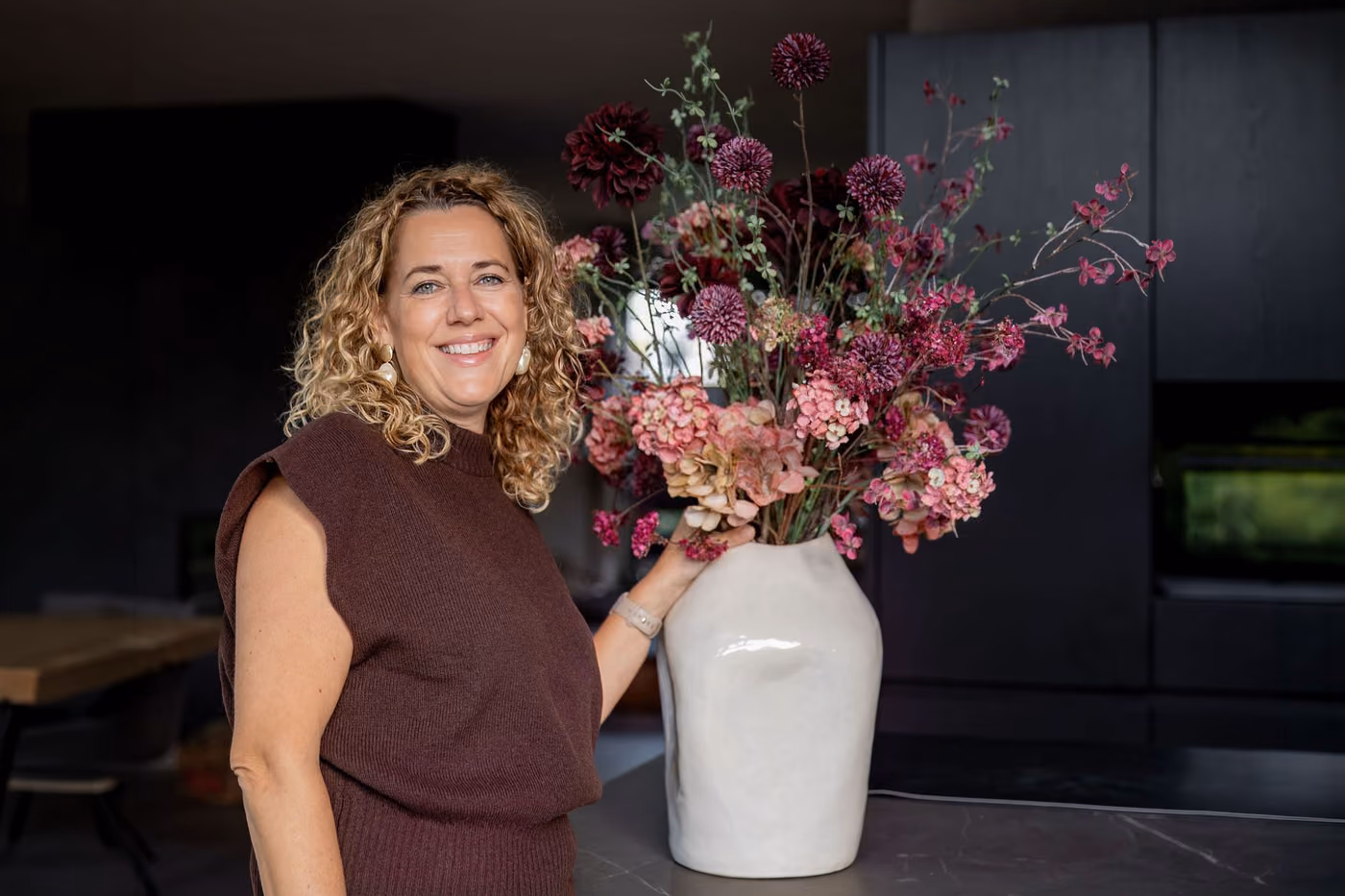 Santine van Leeuwen met een zijden boeket in wijnrode en roze tinten.